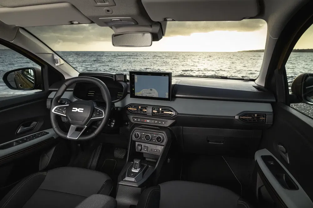 Intérieur moderne d'un Dacia Duster avec écran tactile, face à vue sur mer.