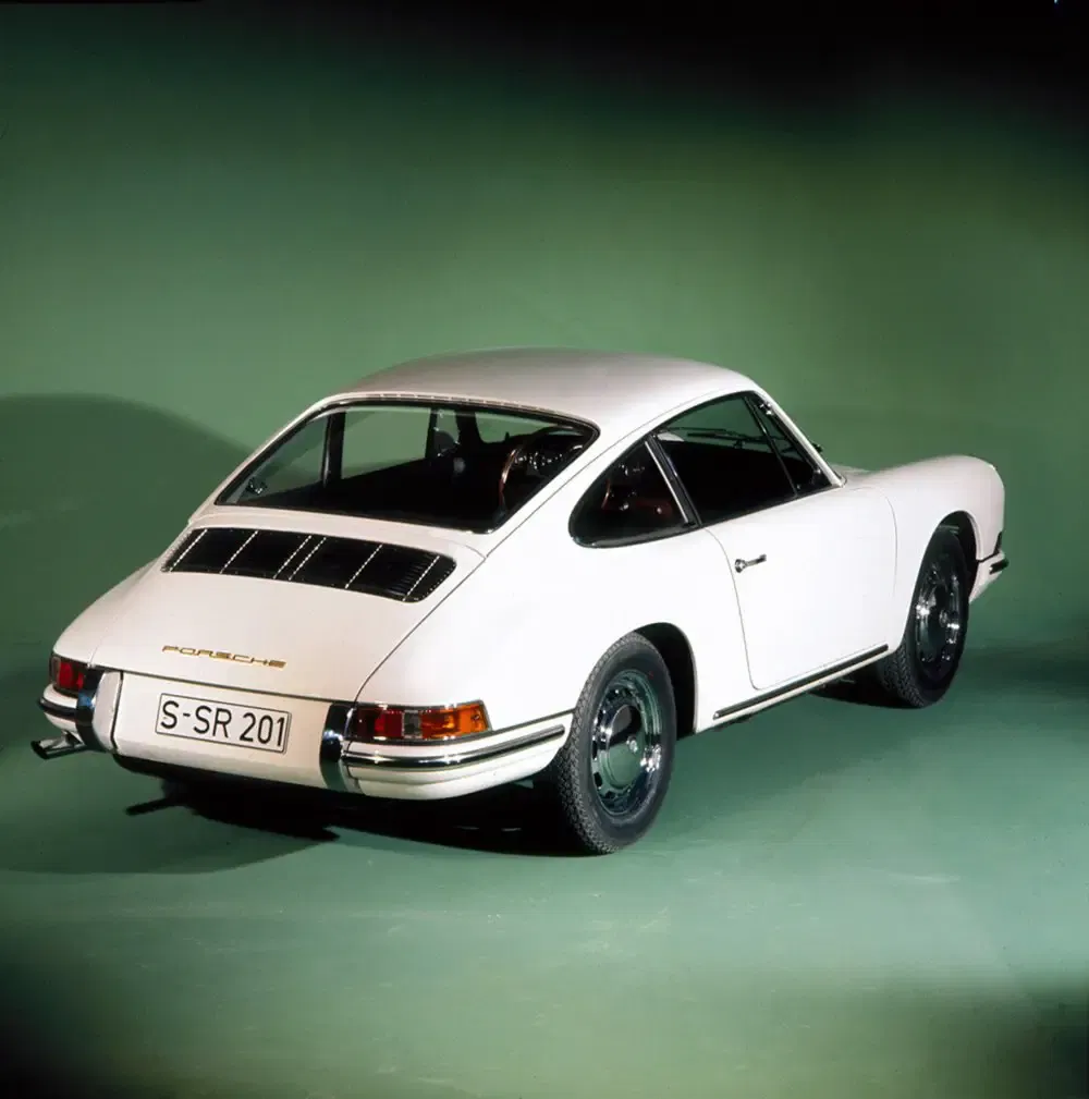 Witte klassieke Porsche 911 achteraanzicht op groene achtergrond.