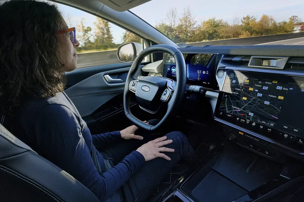 Voiture autonome Ford sur autoroute avec conducteur détendu mains libres.