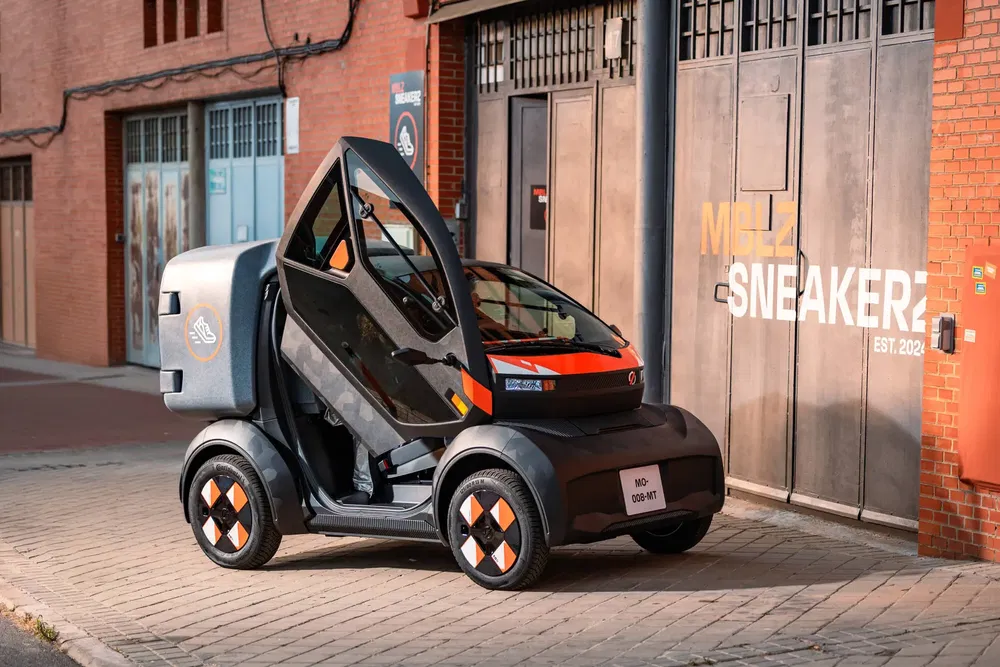 Elektrische microauto met scharniervleugeldeuren open voor stadsgebouw.