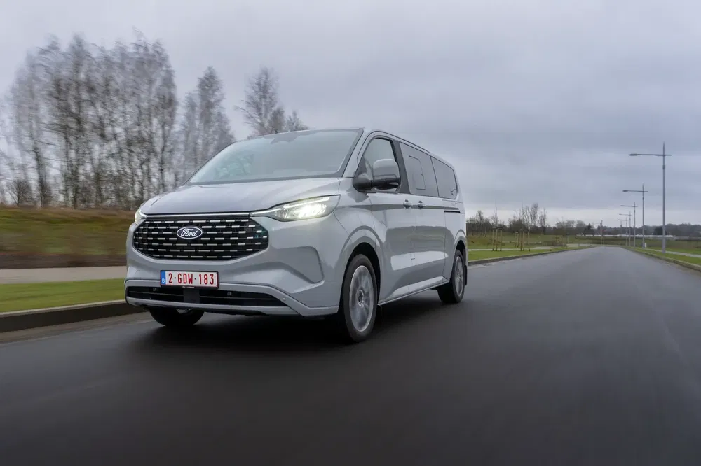 Ford Transit Custom roulant sur une route vide avec un ciel nuageux en arrière-plan.