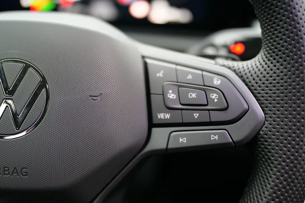 Volkswagen stuurwiel met geïntegreerde multifunctionele knoppen en centraal logo zichtbaar.