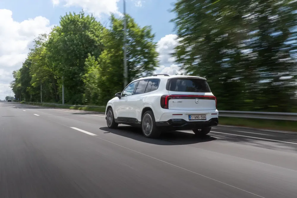 {"fr":"Mercedes EQB blanc roulant sur une autoroute, entouré d'arbres flous en arrière-plan.","nl":"Witte Mercedes EQB rijdt op een snelweg, omgeven door wazige bomen op de achtergrond."}