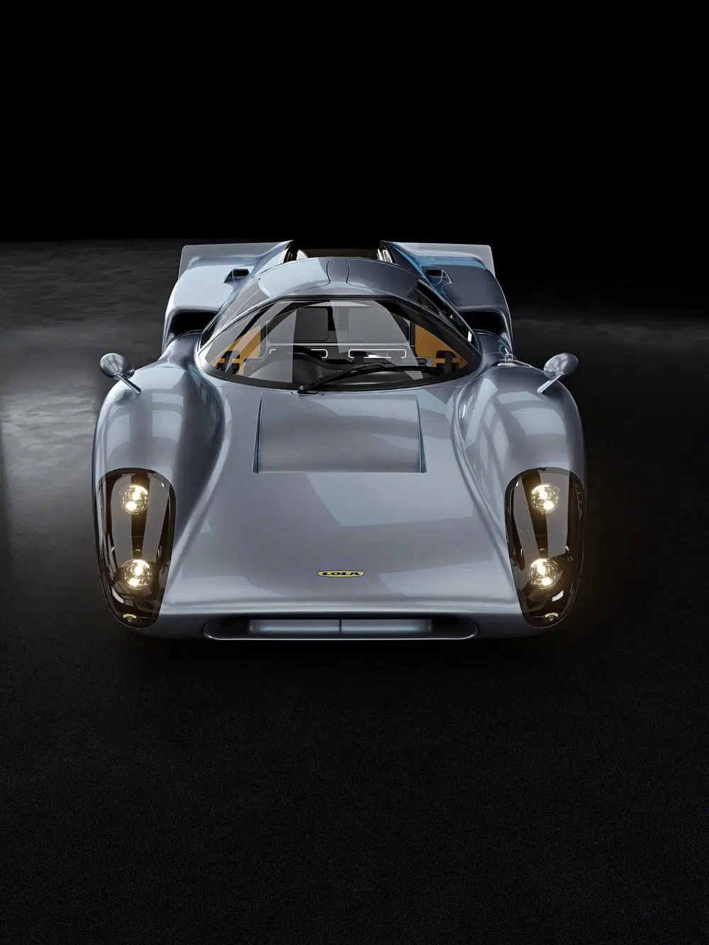 Vooraanzicht van klassieke Lola sportwagen, stijlvolle grijze afwerking, met de lichten aan.