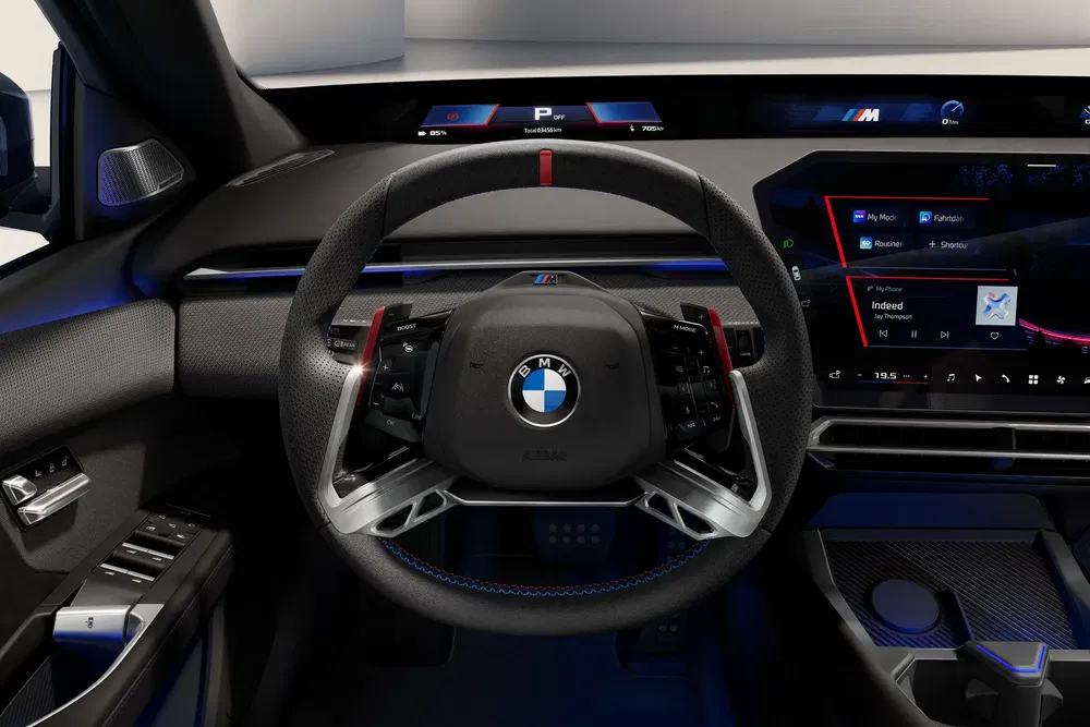 Intérieur de voiture BMW avec volant sportif et tableau de bord numérique high-tech.
