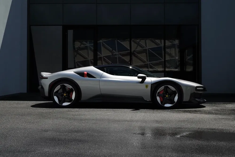 Moderne zilverkleurige Ferrari geparkeerd, sportieve zijkant met elegante lijnen in zonlicht.