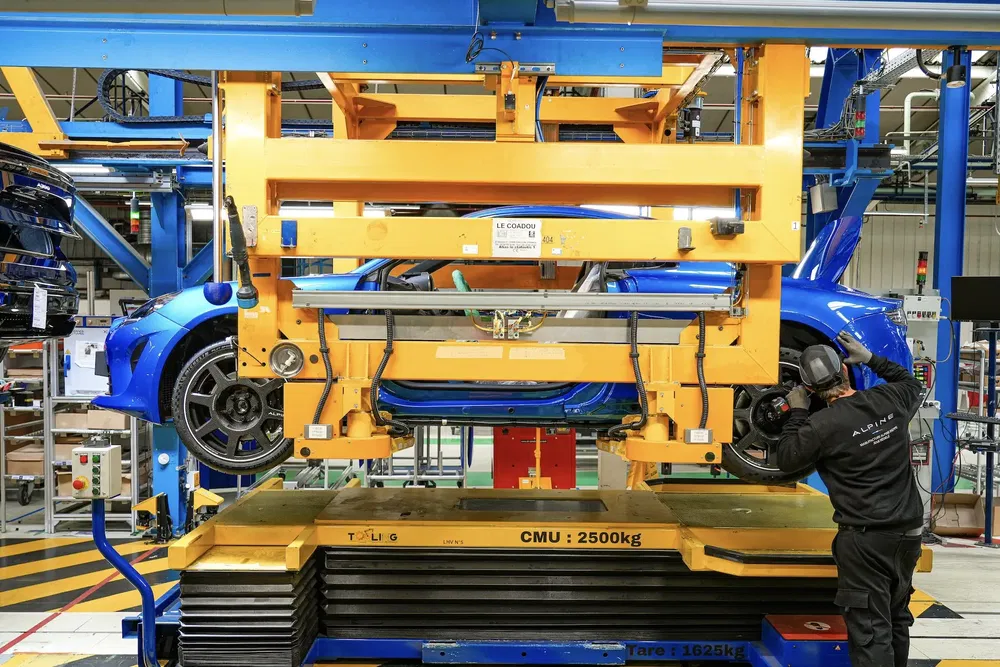 Châssis Alpine A110 sur ligne de montage, usine automobile moderne, technicien en action.