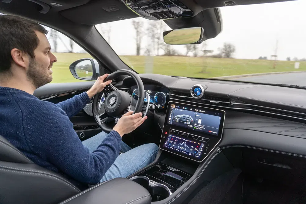 Conducteur dans une voiture moderne avec tableau de bord numérique et écran tactile.