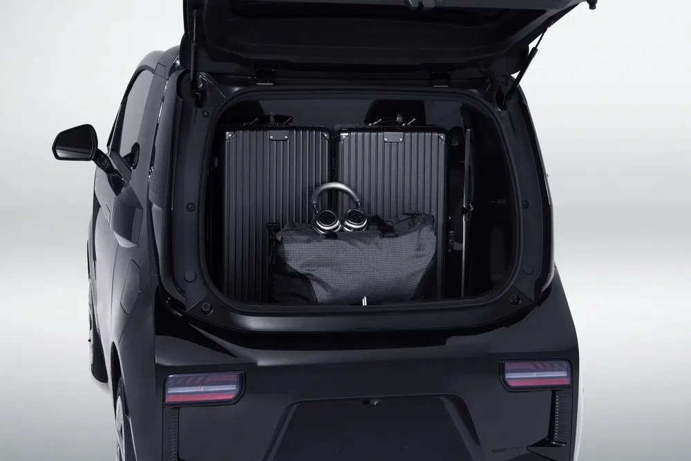 Coffre arrière d'une voiture électrique avec valises et sac de voyage.