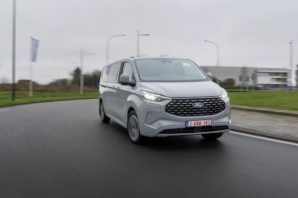 Ford Transit Custom blanc sur route urbaine, journée grise et brumeuse.