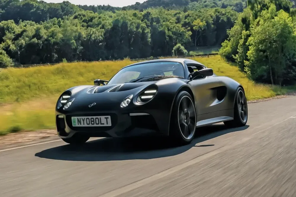 Voiture sportive noire en mouvement sur route de campagne, voiture moderne avec design aérodynamique.