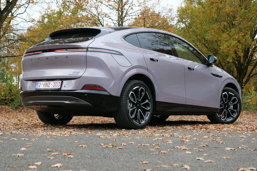 SUV XPeng G6 électrique garé sur une route d'automne bordée d'arbres.