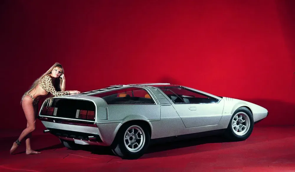 Femme posant avec une Lamborghini Marzal argentée sur fond rouge vif.