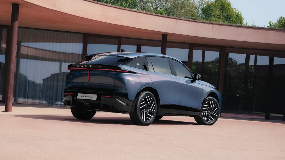 SUV électrique Lancia bleu métallisé garé près d'une maison moderne.