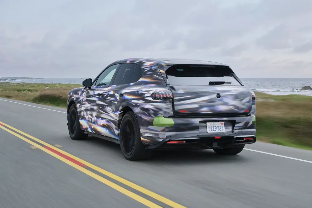 {"fr":"Prototype Porsche Macan 2024 camouflé roulant sur une route côtière.","nl":"Verhulde prototype van de Porsche Macan 2024 rijdt op een kustweg."}