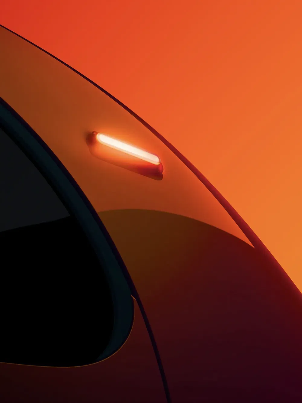 Détail lumineux du feu arrière d'une Tesla Model Y sur fond orange vibrant.