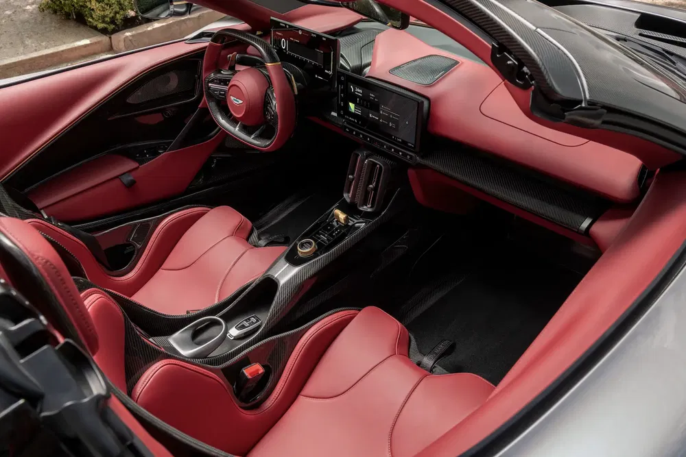 Intérieur d'une hypercar avec des sièges en cuir rouge et tableau de bord moderne.