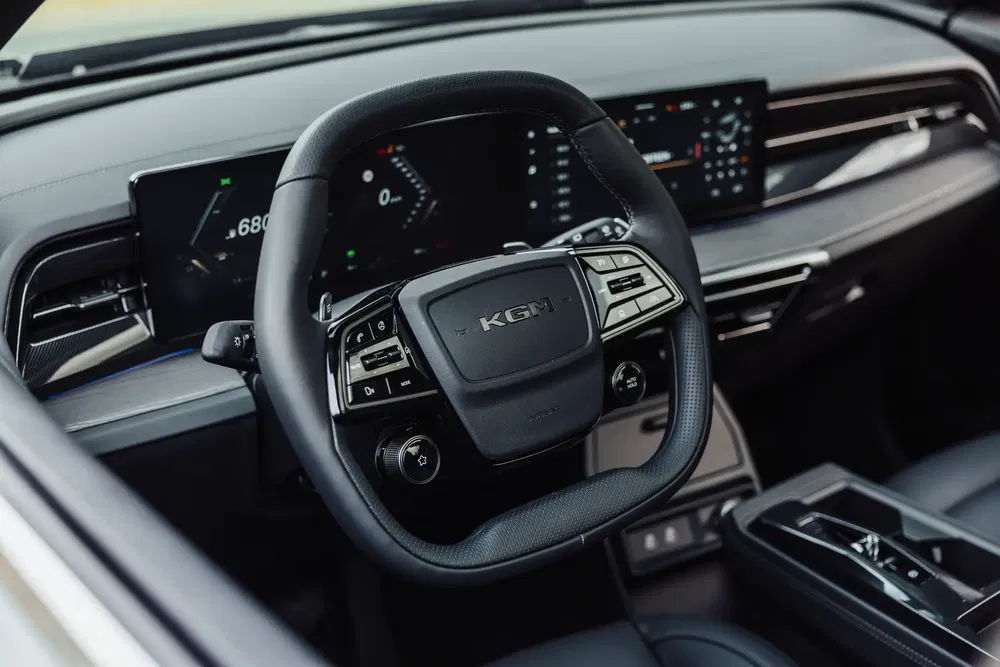 Moderne interieur van een KGM-auto met ergonomisch stuurwiel en digitaal dashboard.
