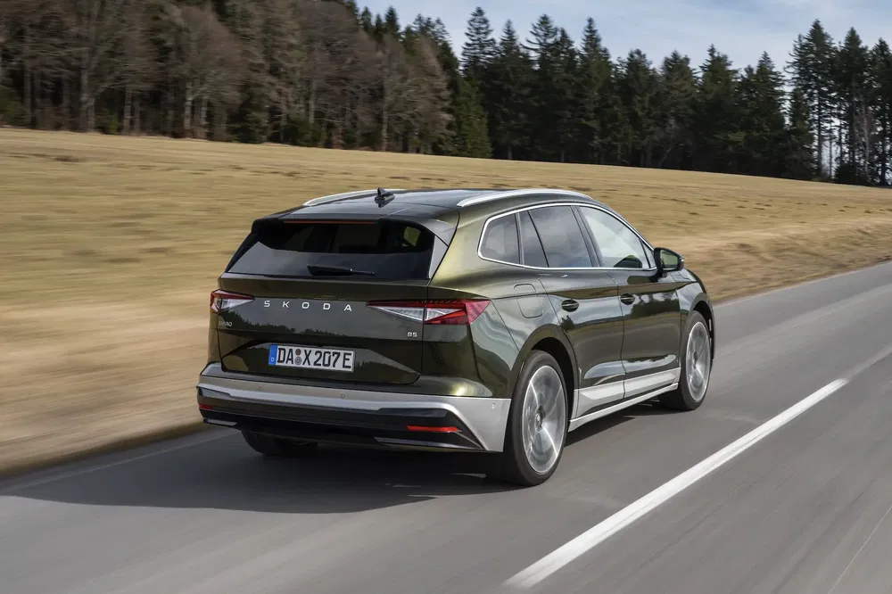 Skoda Enyaq iV roulant sur une route de campagne, arrière et polyvalence électrique visibles.
