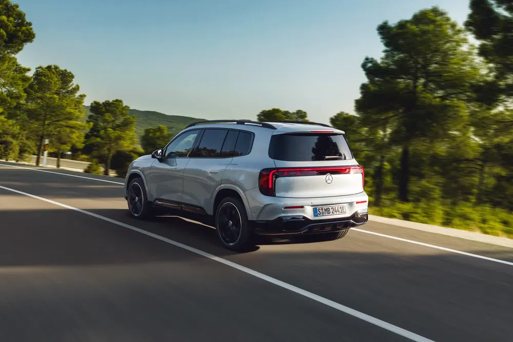 Mercedes GLB argenté sur une route bordée d'arbres, capturé depuis l'arrière en mouvement.