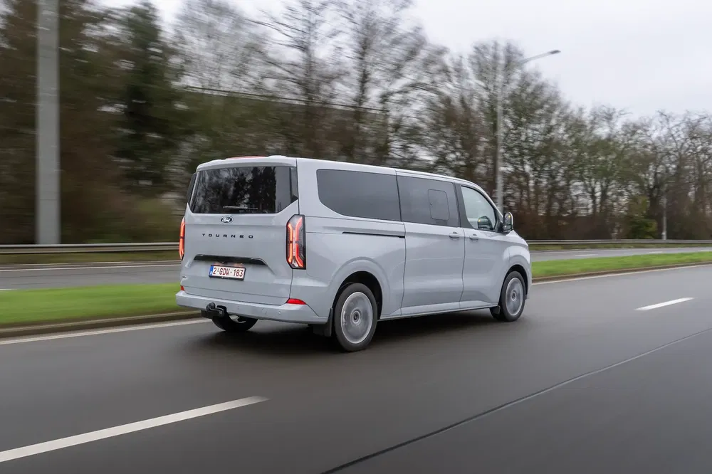 Hyundai Staria grise circulant sur une route, accent sur le design arrière spacieux du fourgon.