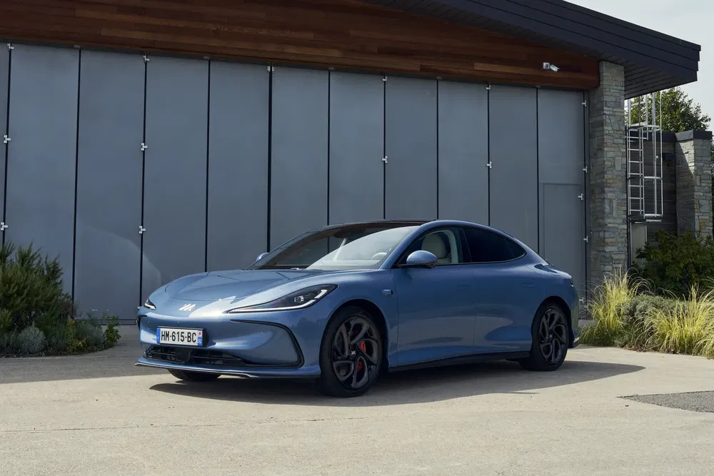 Voiture de sport MG bleue garée devant un bâtiment moderne.