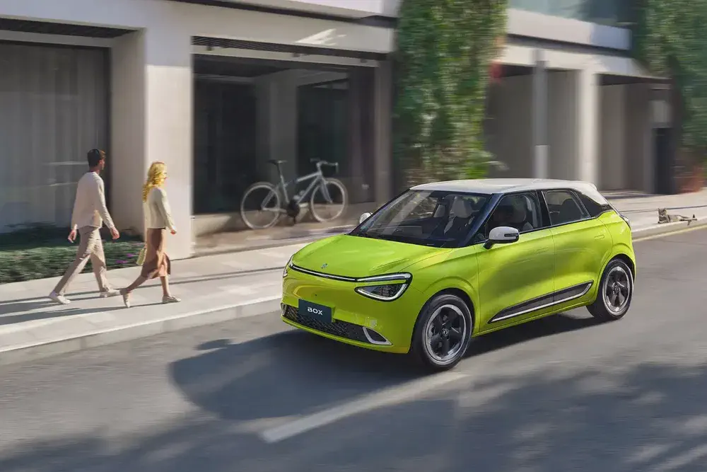 Voiture électrique MG 3 EX verte, circulant sur une rue urbaine moderne.