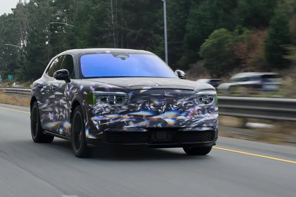 SUV camouflé sur autoroute, arbres en arrière-plan, test de conduite en cours.