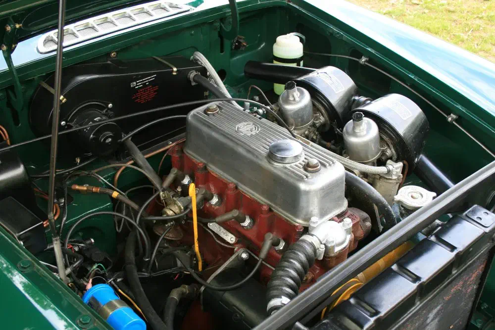 Compartiment moteur d'une voiture classique MG, avec moteur quatre cylindres facilement visible.