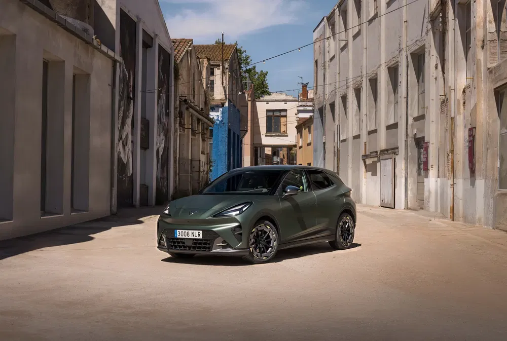 Cupra Born vert dans une ruelle industrielle, architecture urbaine minimaliste.
