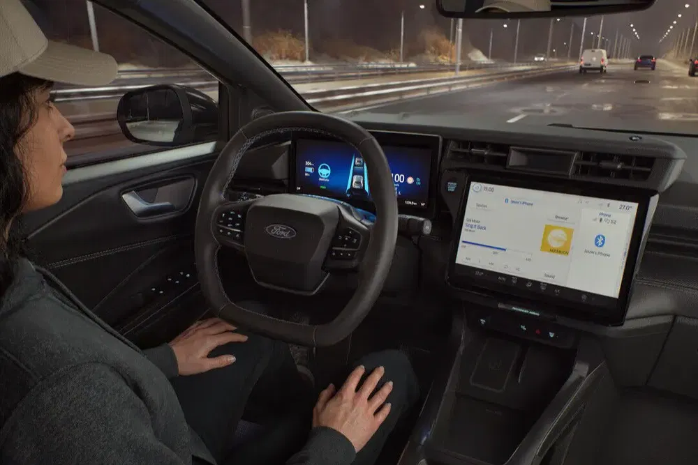 Voiture Ford avec technologie de conduite autonome sur route de nuit, passager détendu.