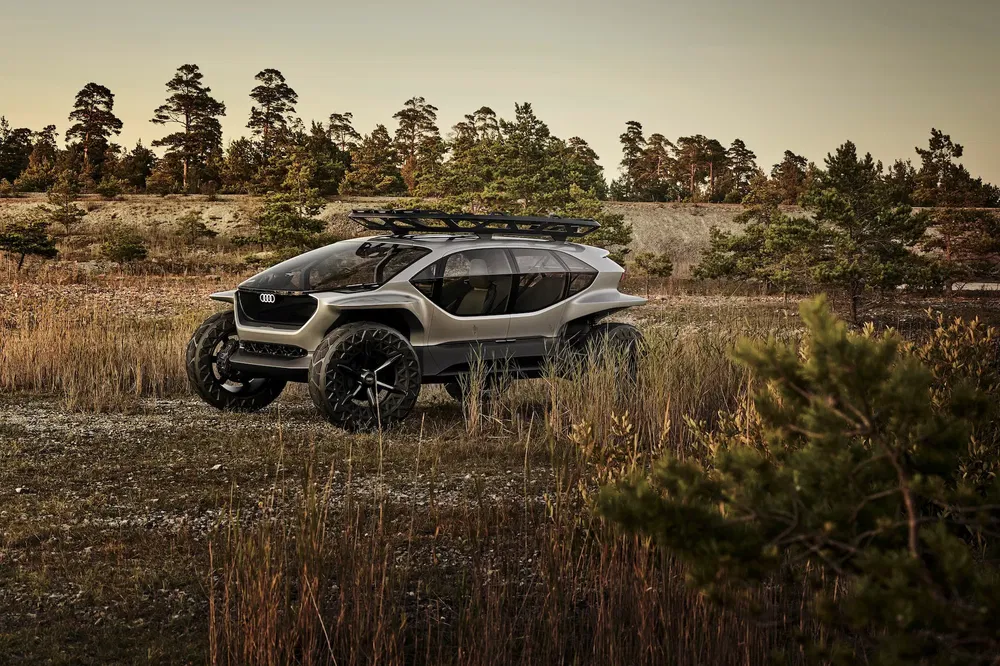 Concept-car Audi tout-terrain gris avec jantes noires, en pleine nature boisée.