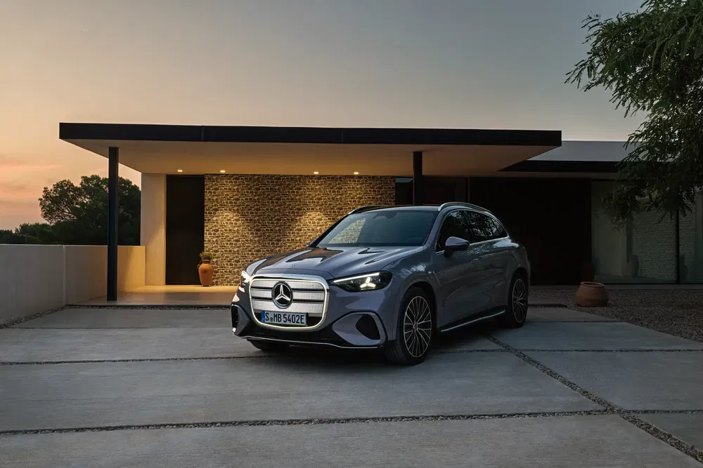 Mercedes-Benz geparkeerd voor een moderne villa bij schemering, subtiele verlichting benadrukt elegante lijnen.