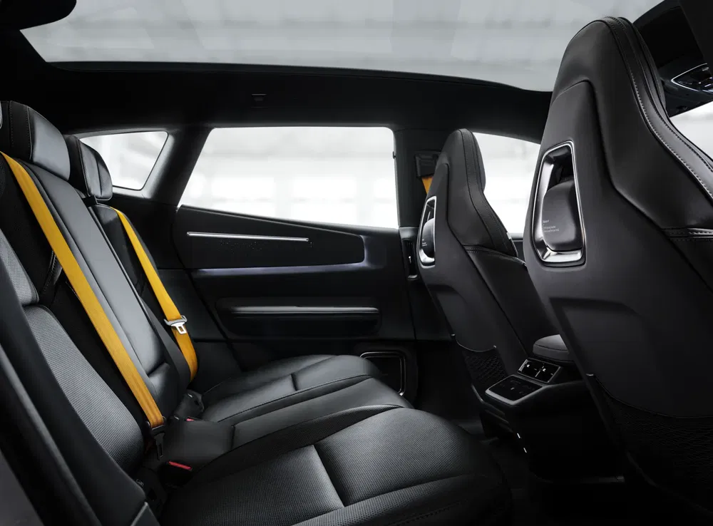 Intérieur luxueux d'une voiture avec sièges en cuir noir et ceintures de sécurité jaunes.
