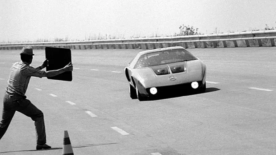 Prototype Mercedes-Benz C111 sur circuit d'essai avec un photographe en action.