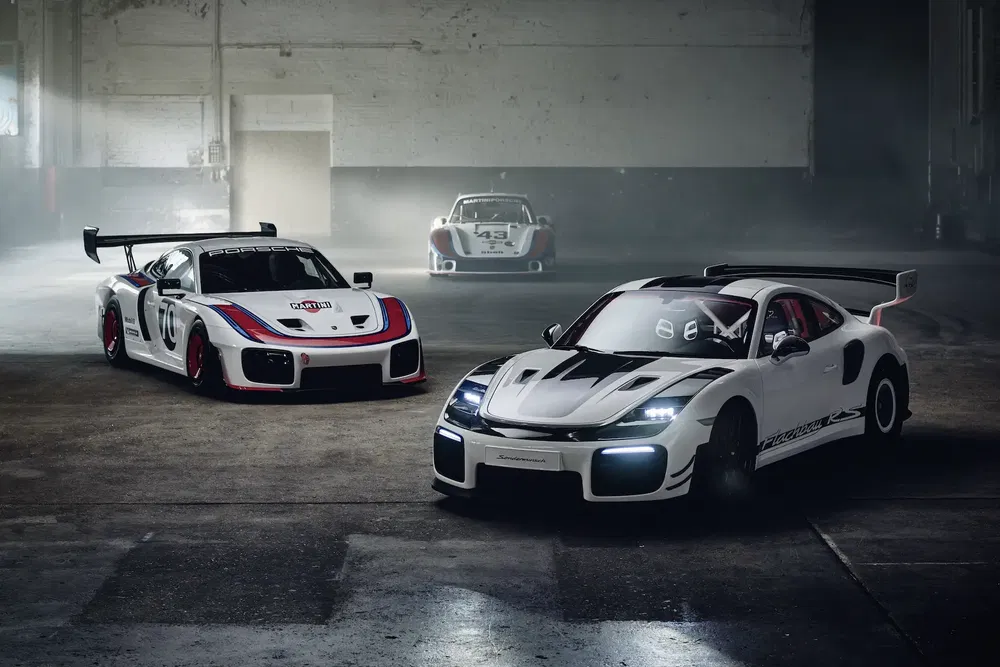 Trois Porsche 935 blanches sportives garées dans un entrepôt sombre et industriel.