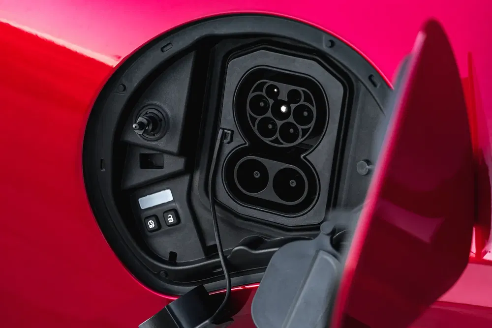 Prise de recharge sur une voiture électrique rouge, détail moderne et technologique.