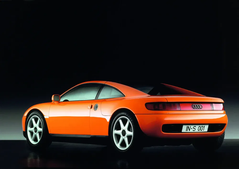 Oranje Audi Avus conceptauto, achterkant zicht, donkere achtergrond, futuristisch elegant design.
