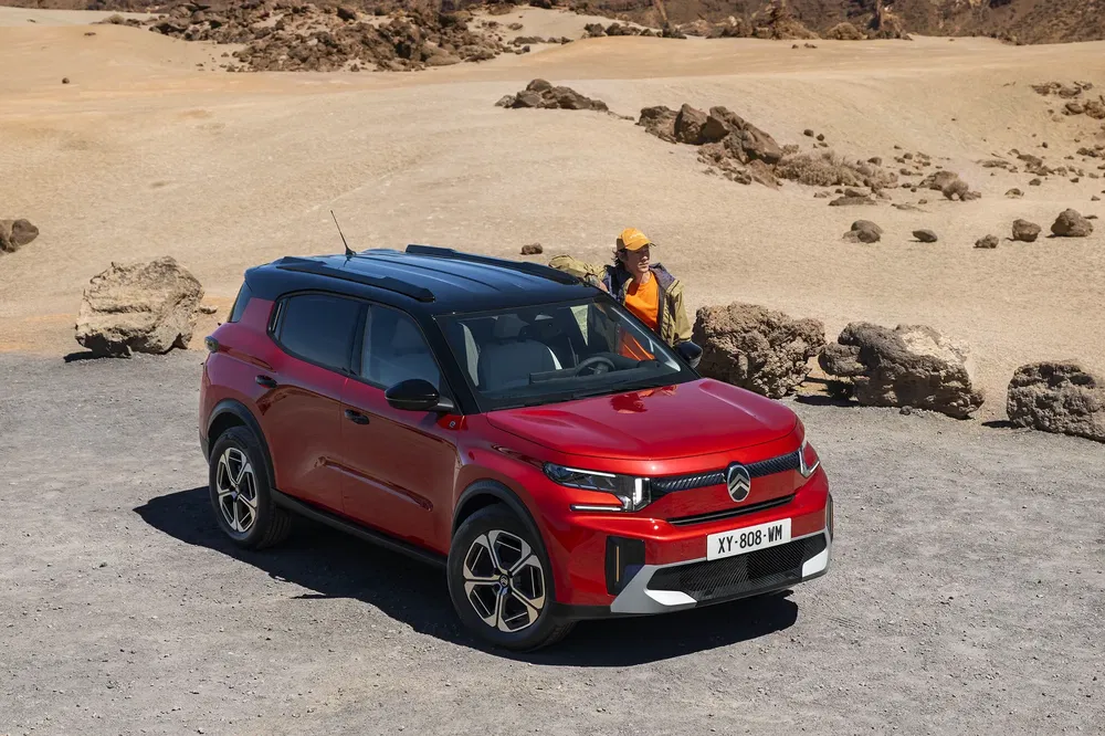 Rode Citroën C3 Aircross op een woestijnachtig terrein met bestuurder op de achtergrond.