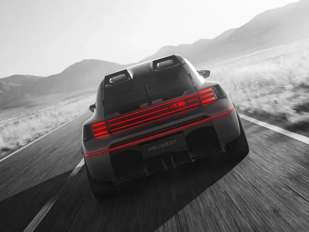 Peugeot concept-car GT noir roulant sur route désertique, lumière arrière LED rouge distinctive.