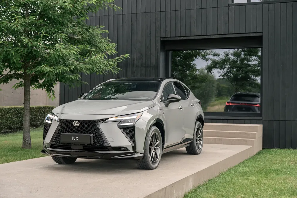 Lexus NX gris devant maison moderne, esthétique élégante et design architectural.