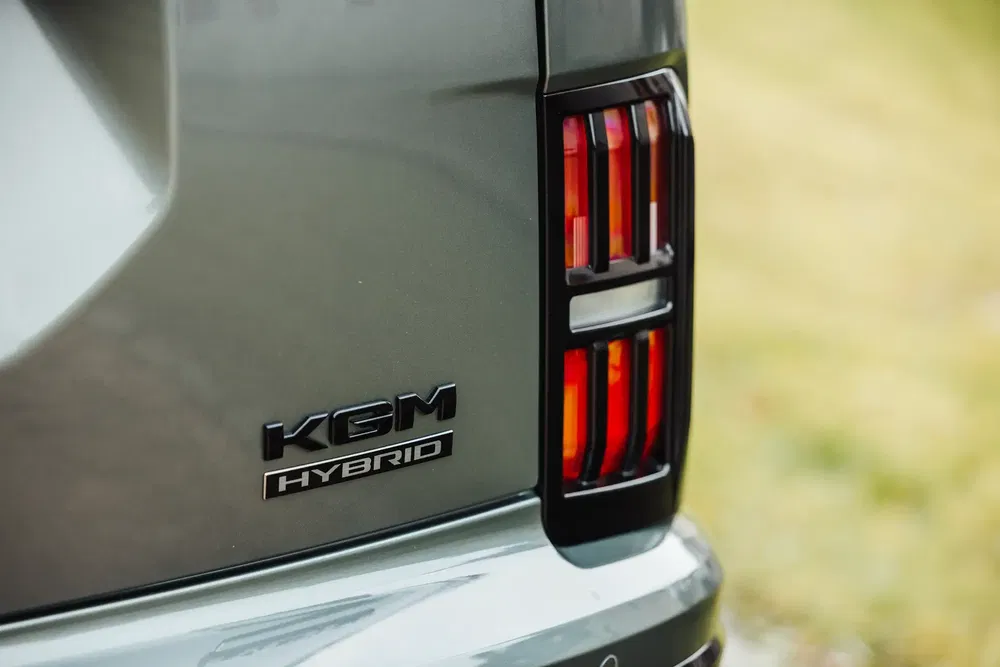 Feux arrière et badge KGM Hybrid sur un véhicule gris, détail hybride moderne.