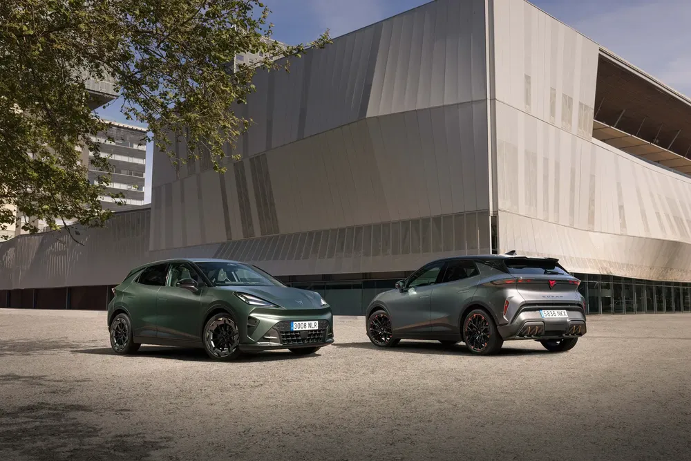 Deux Cupra Tavascan vertes stationnées devant un bâtiment moderne, en pleine lumière du jour.