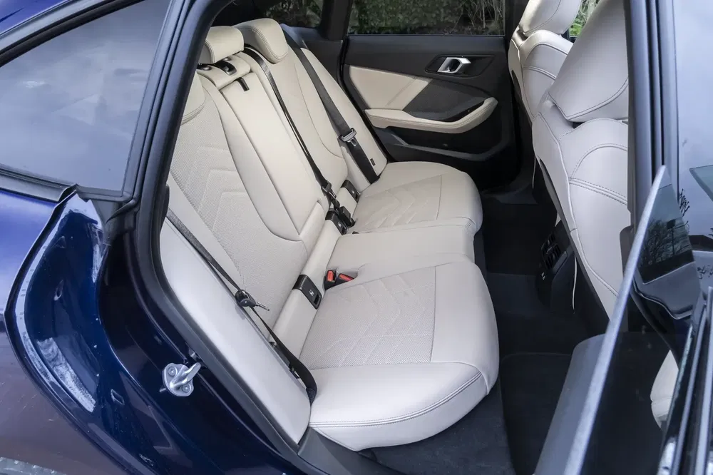 Habitacle arrière BMW, sièges en cuir beige, design intérieur luxueux et spacieux.