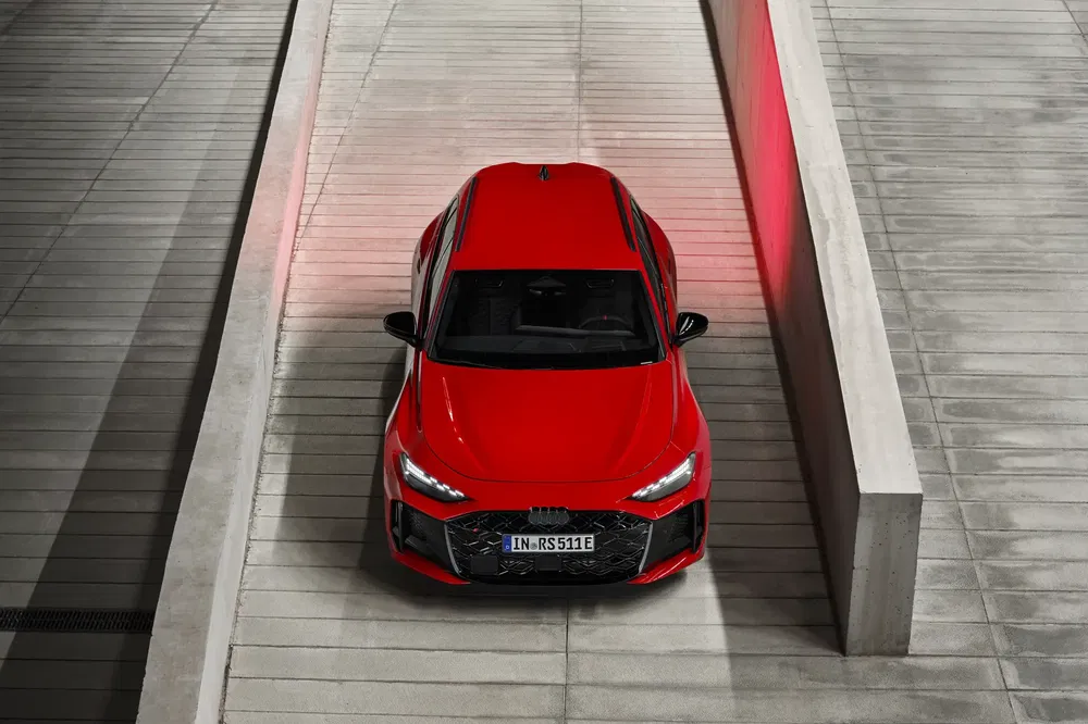 Rode Audi RS7 Sportback met futuristisch ontwerp geparkeerd tussen betonnen muren.