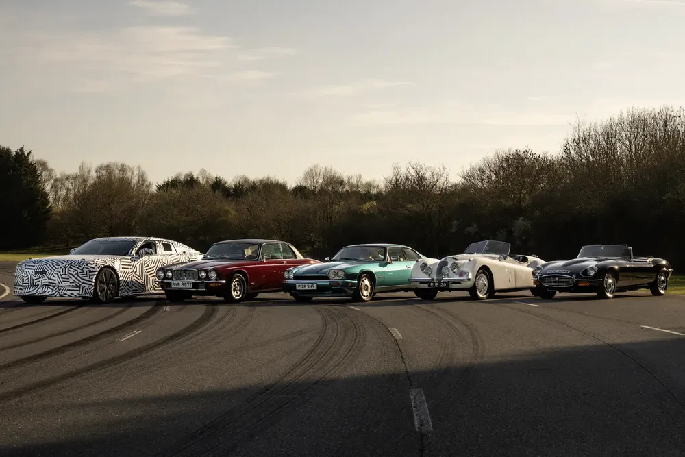 Opstelling van klassieke en moderne Jaguar-auto's op een buitenracebaan.
