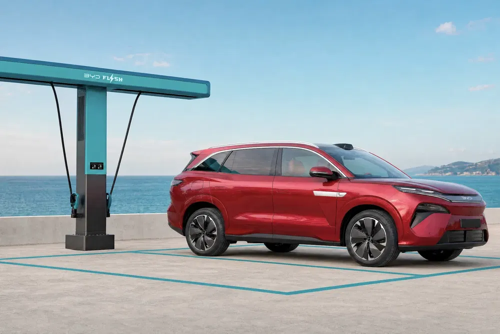 Voiture électrique BYD SUV rouge en charge près de la mer avec borne de recharge BYD.