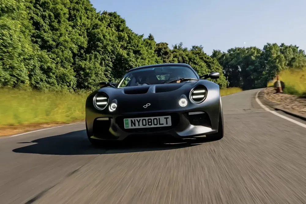 Voiture de sport noire en mouvement sur route sinueuse, journée ensoleillée.