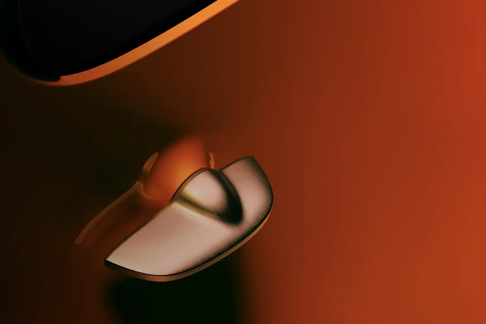 Poignée de porte de voiture moderne sur carrosserie orange, design élégant et aérodynamique.