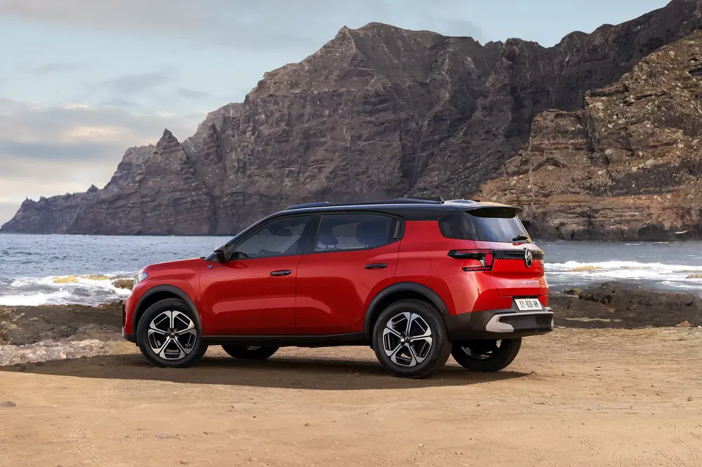 Rode Renault Austral SUV geparkeerd voor een klif met de oceaan op de achtergrond.